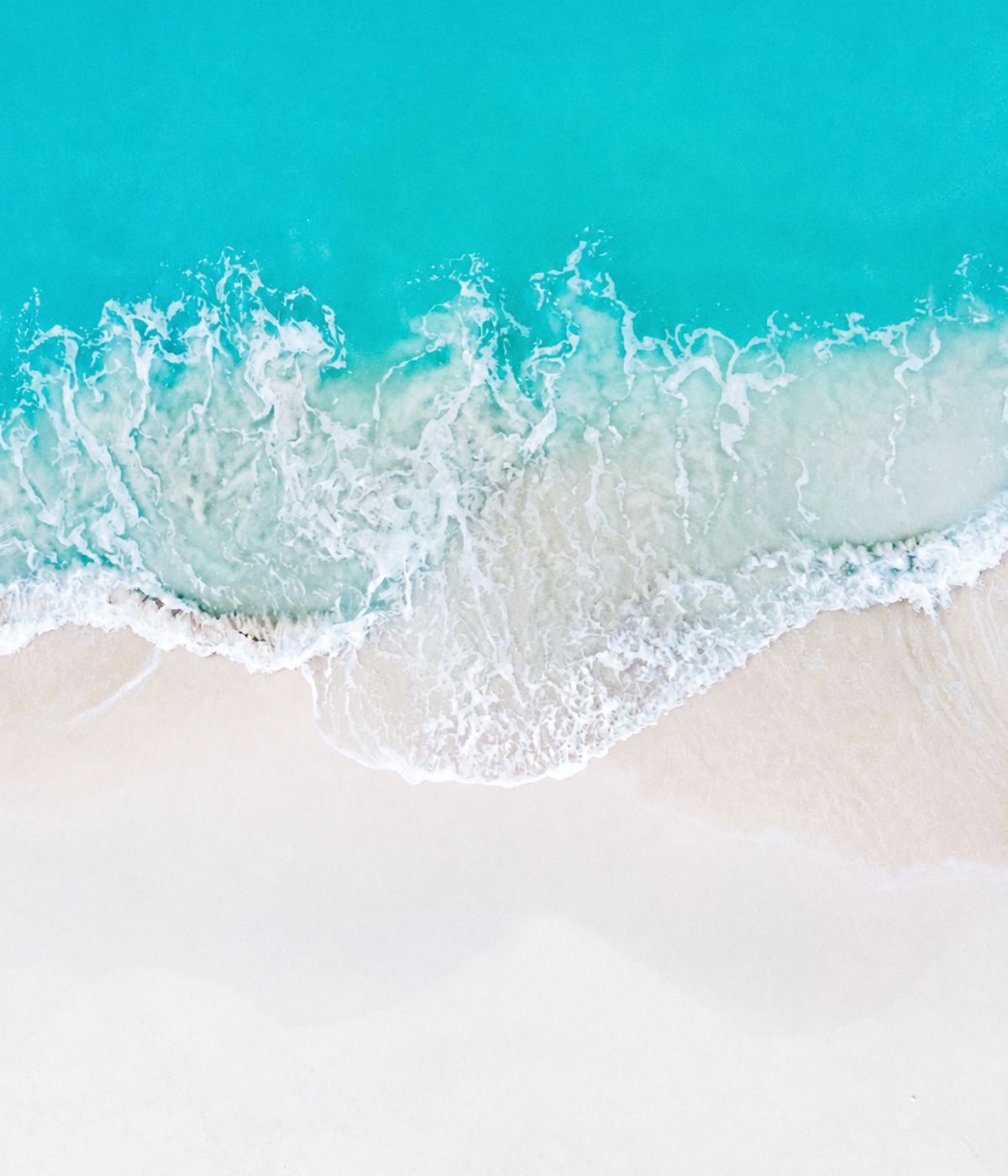 Turquoise water breaking onto white sand