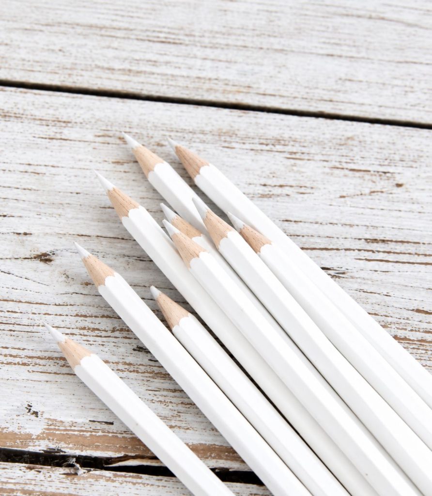 White pencils lying on pale weathered wood